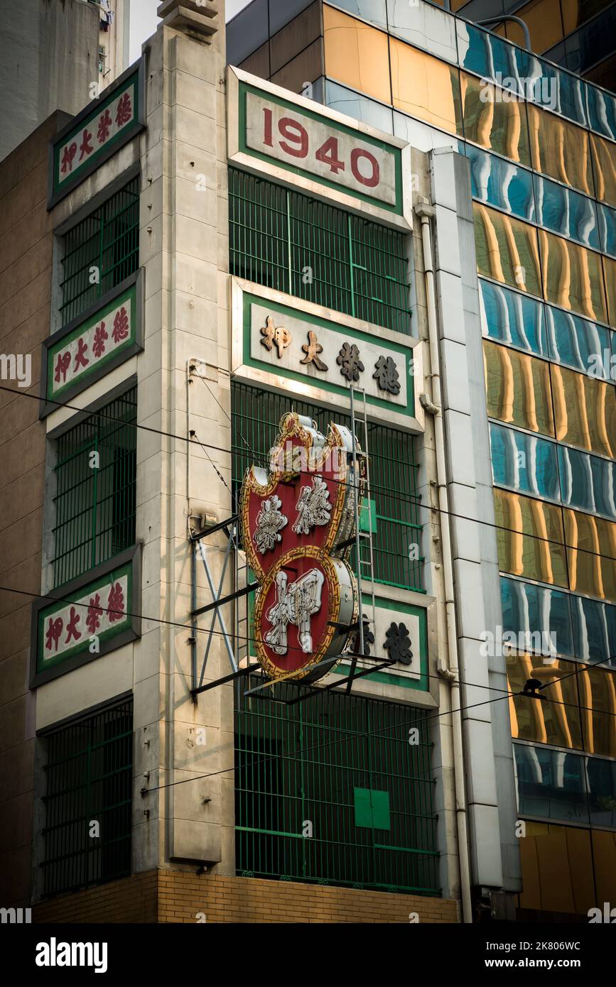 Außenansicht des Tak Wing Pawn Shop, eines traditionellen chinesischen Pfandladens in einem „tong lau“-Shophaus neben einem modernen Hochhausgebäude, Central, Hon Stockfoto