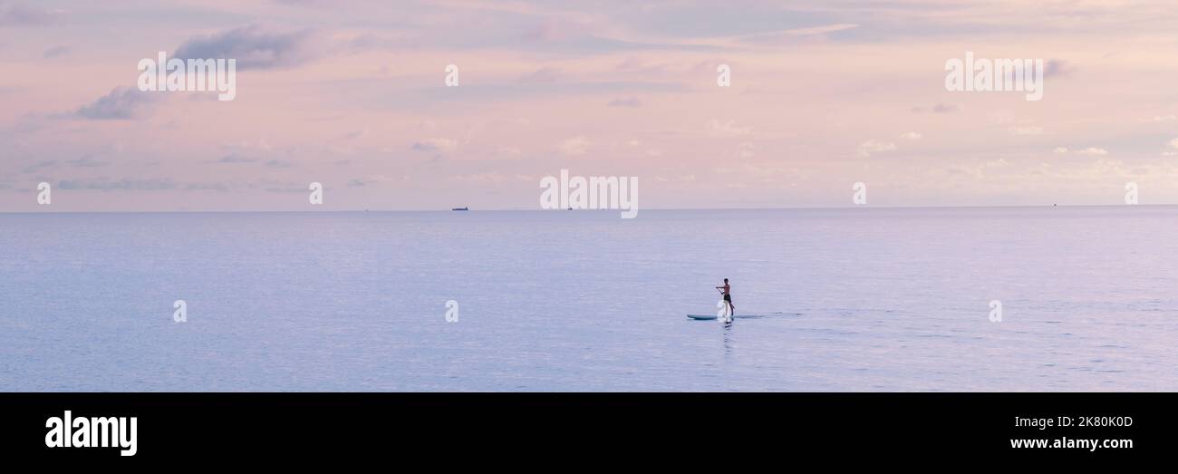 Männer paddeln während des Sonnenuntergangs auf einem Brett auf Koh Kood, einer tropischen Insel in der Provinz trat Ost-Thailand Stockfoto