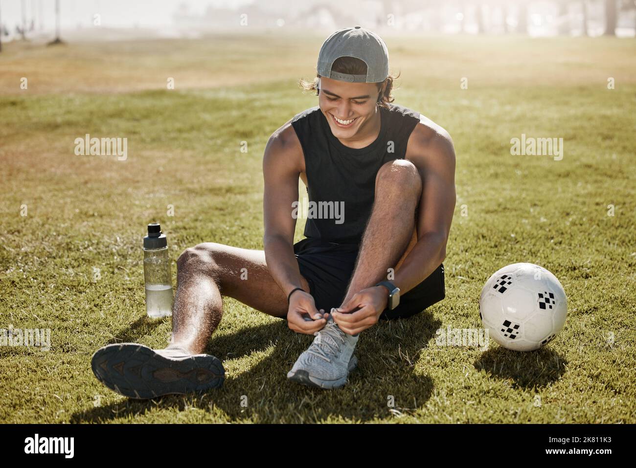 Sport-, Fußball- und Männerschuhe werden vor Spiel, Wettkampf oder Fitnessübungen auf dem Rasenplatz im Freien geschnürte. Wellness Gesundheit, Ball und Athletenfußball Stockfoto