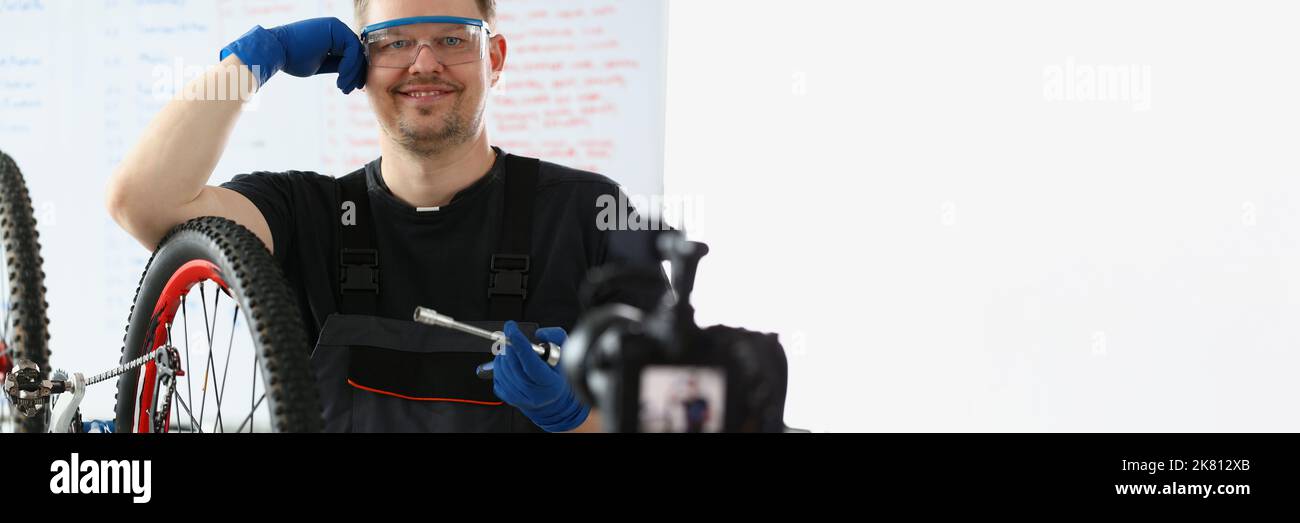 Glücklicher Handwerker versuchen, gebrochenes Fahrrad zu reparieren, Film-Prozess auf Videokamera Stockfoto
