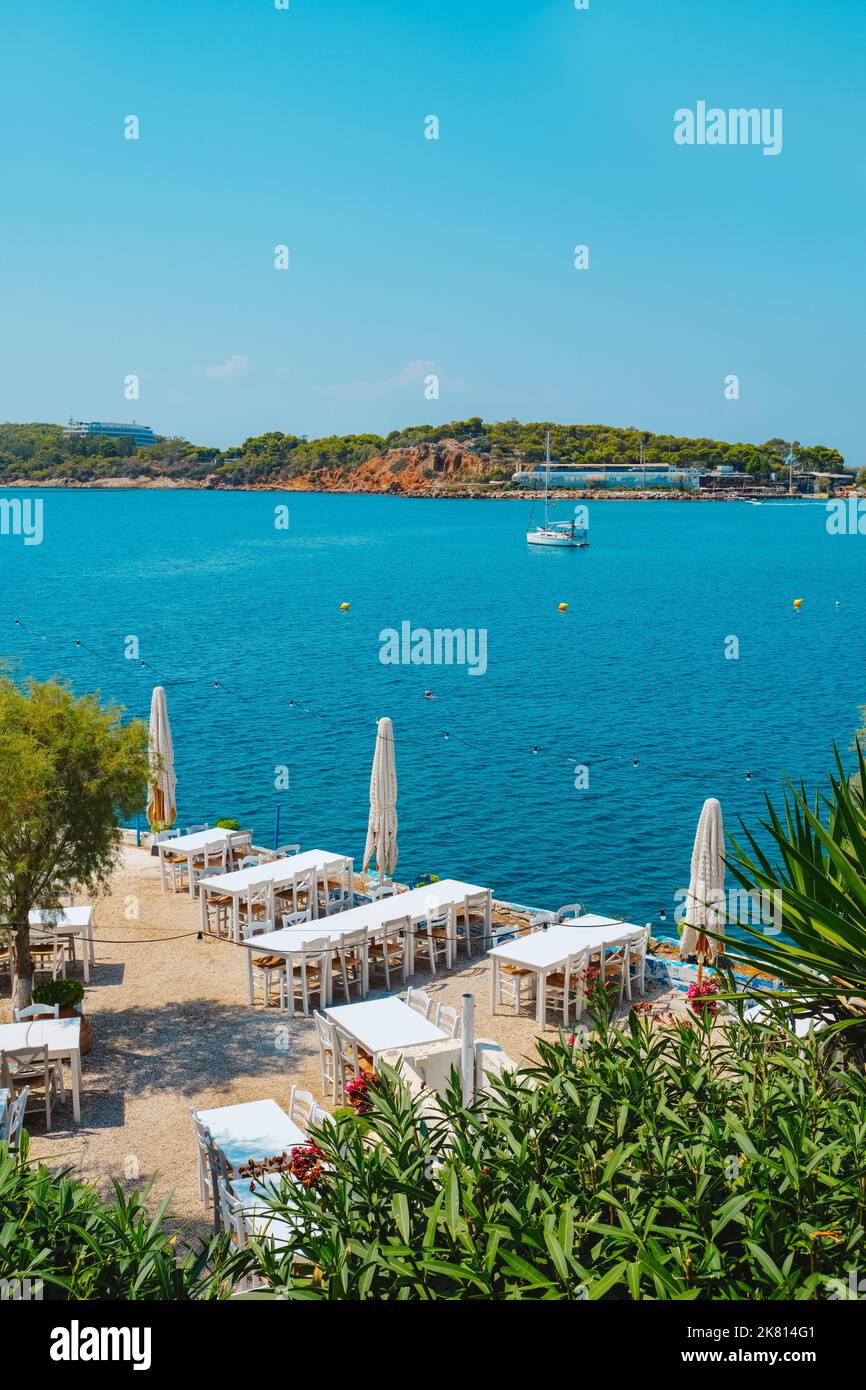 Die Tische eines einsamen Restaurants am Mittelmeer in der Bucht von Vouliagmeni in Vouliagmeni, Griechenland Stockfoto