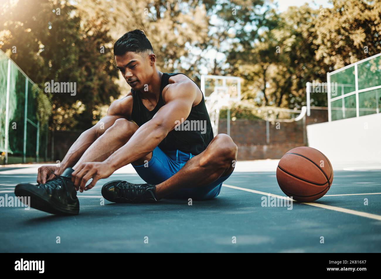 Basketballplatz, Mann und Schuhe bereiten sich auf das Training in der Freizeit- und Sportanlage vor. Sport-, Bewegungs- und Fitness-Mann mit Schnürband, der sich bereit macht Stockfoto