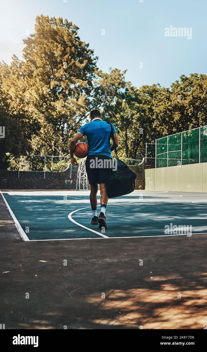 Basketballspieler, Fitnesssportler und Spazierengehen mit Geräten auf dem Platz im Freien. Afroamerikanischer Sportmann, gesunde Ballübung Motivation Stockfoto