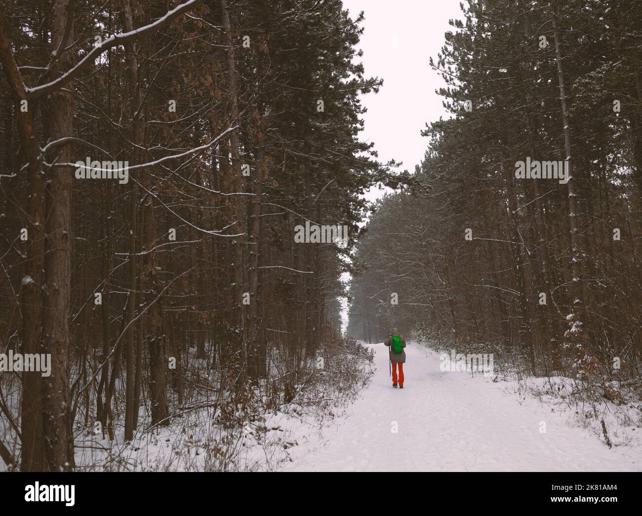 Person setzt sich mit Ausrüstung auf eine Bergstraße im Schnee Stockfoto