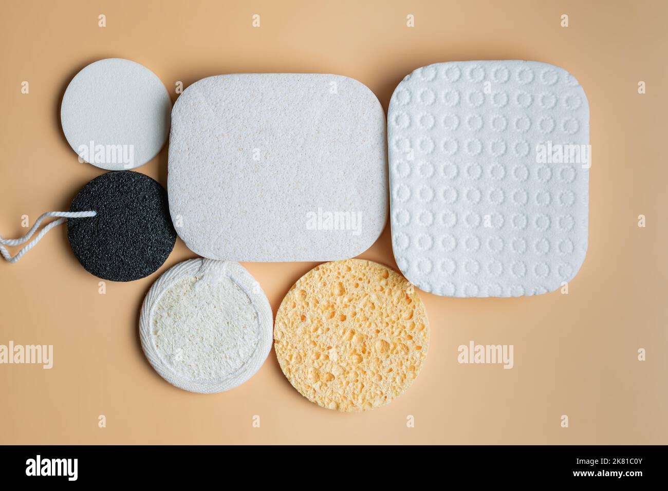 Auswahl an Gesichtsschwämmen auf beigefarbenem Hintergrund. Runde und quadratische Gesichtsschwämme aus natürlichen ökologischen Materialien für eine hygienische Selbstpflege Stockfoto