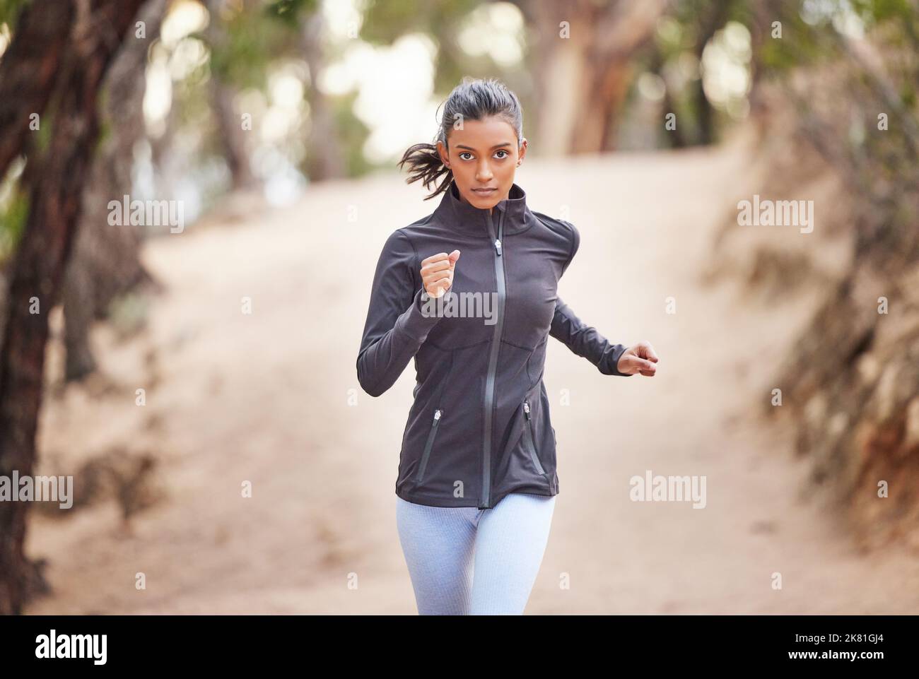 Eine junge Frau, die durch einen Wald joggt. Stockfoto