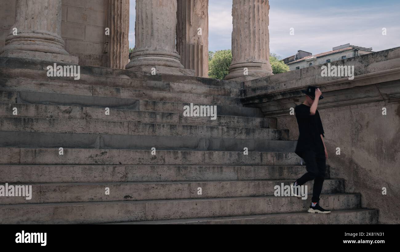 Ein Mann, der die Treppe in Maison Carree in Nimes, Frankreich, hinuntergeht. Frühling in Südfrankreich. Stockfoto