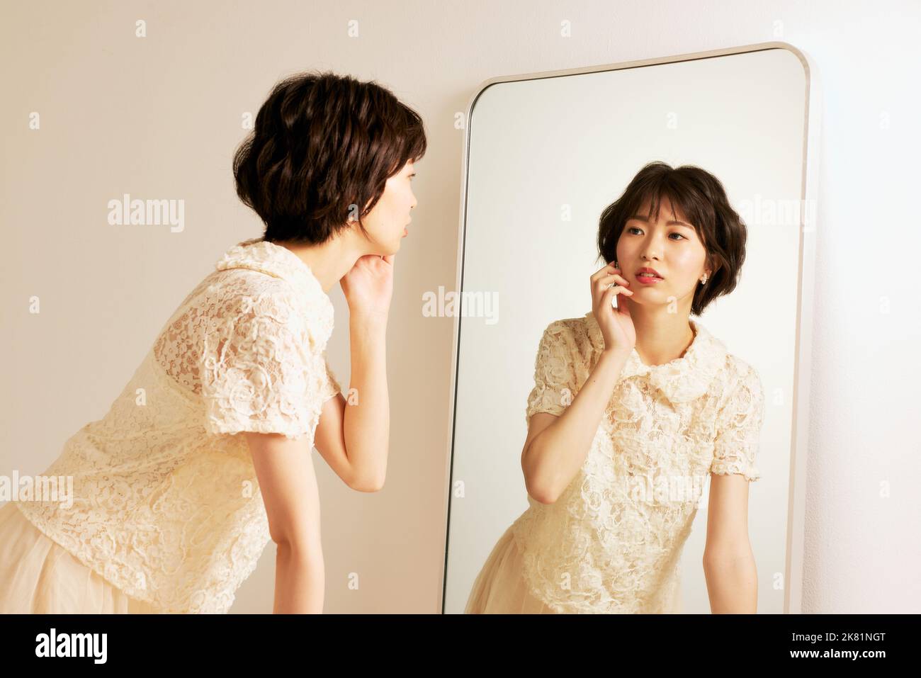 Junge japanische Frau, die in den Spiegel schaut Stockfoto