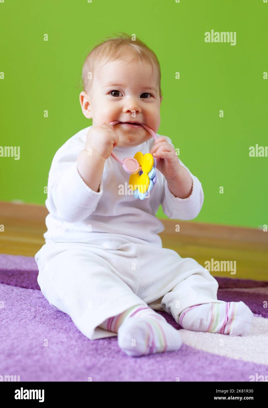 Nette Schönheit Baby Kind sitzen Zimmer und kauen Spielzeug Stockfoto