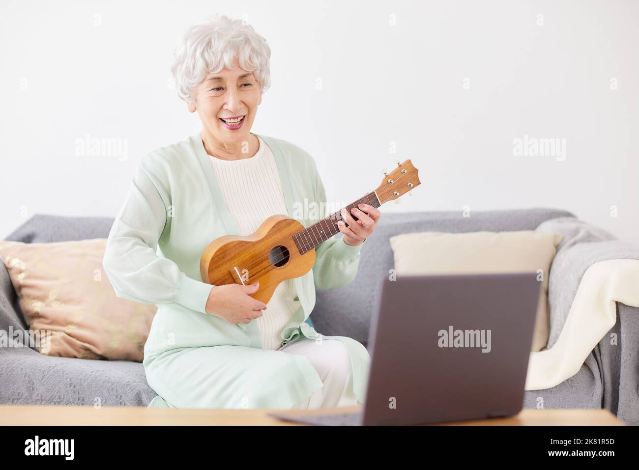 Japanische ältere Frau spielt Ukulele Stockfoto