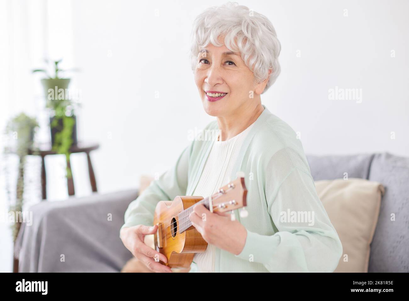 Japanische ältere Frau spielt Ukulele Stockfoto