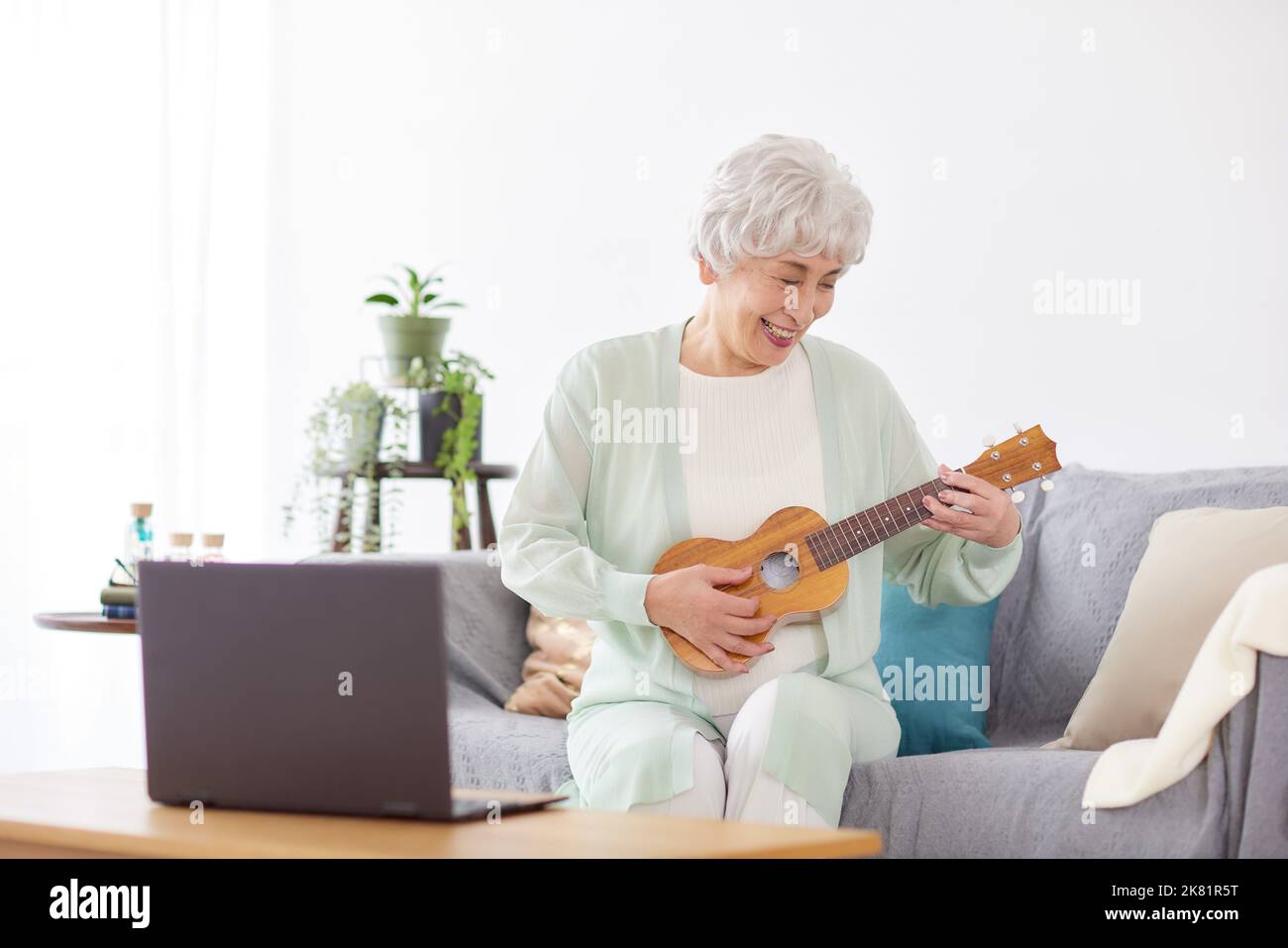 Japanische ältere Frau spielt Ukulele Stockfoto