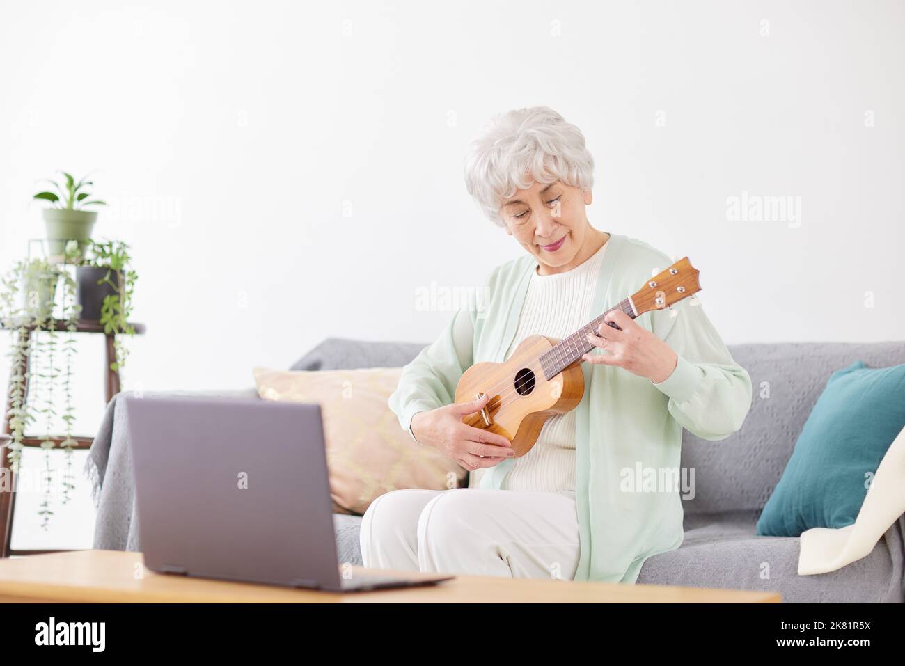 Japanische ältere Frau spielt Ukulele Stockfoto