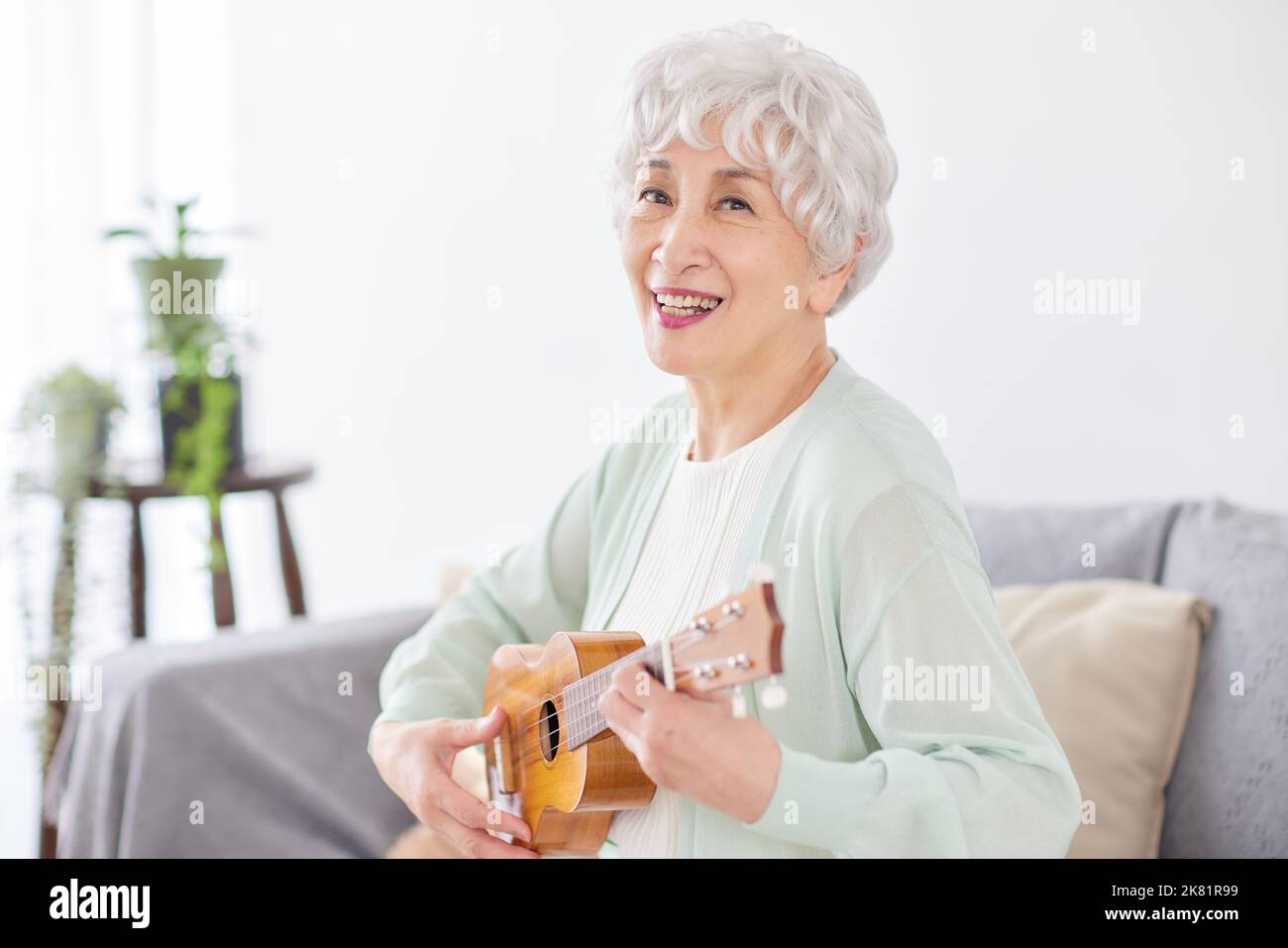 Japanische ältere Frau spielt Ukulele Stockfoto