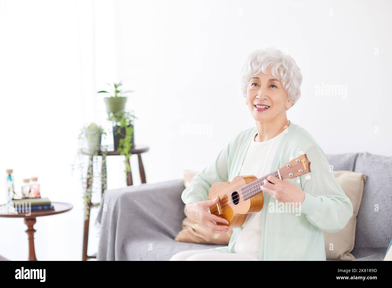 Japanische ältere Frau spielt Ukulele Stockfoto