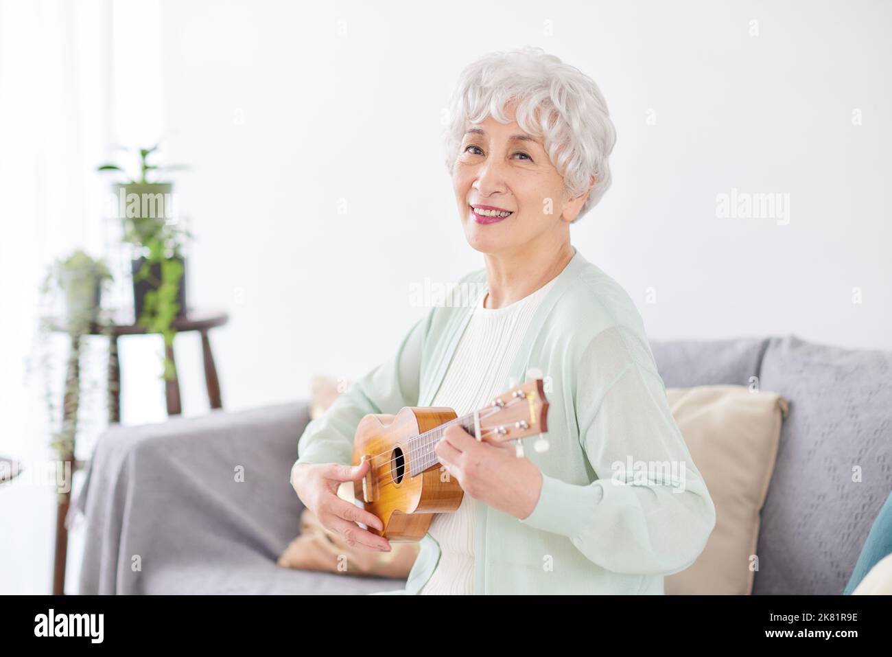 Japanische ältere Frau spielt Ukulele Stockfoto