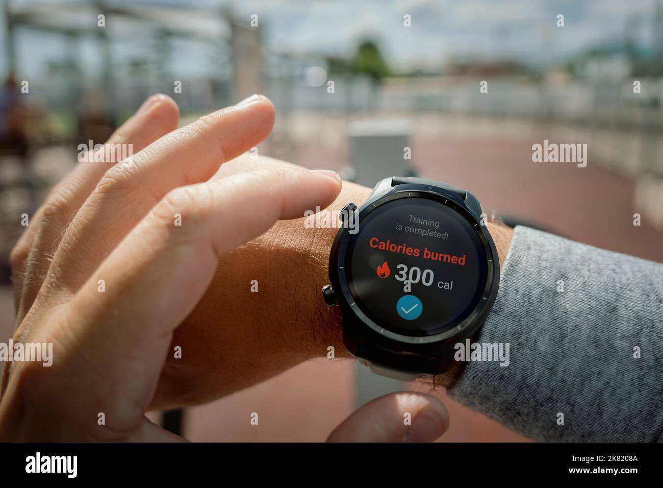 Ein Mann im Stadion überprüft die Anzahl der verbrannten Kalorien in seiner Smartwatch. Tägliche Bewegung an der frischen Luft für die Gewichtsabnahme. Intelligente Gadgets für den Sport Stockfoto