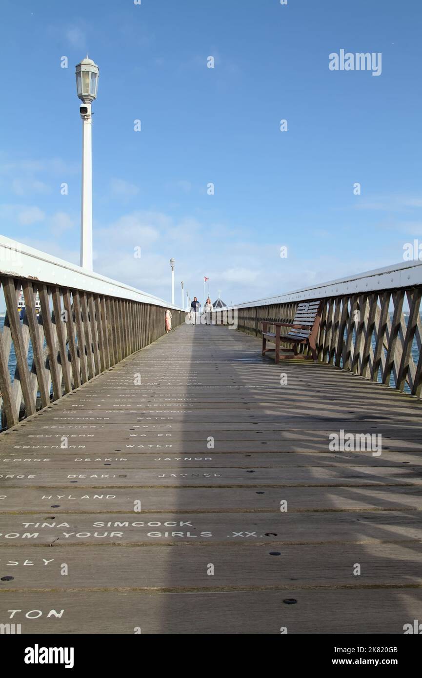 Zwei Personen gehen auf dem hölzernen Yarmouth Pier, Yarmouth, Isle of Wight uk Stockfoto