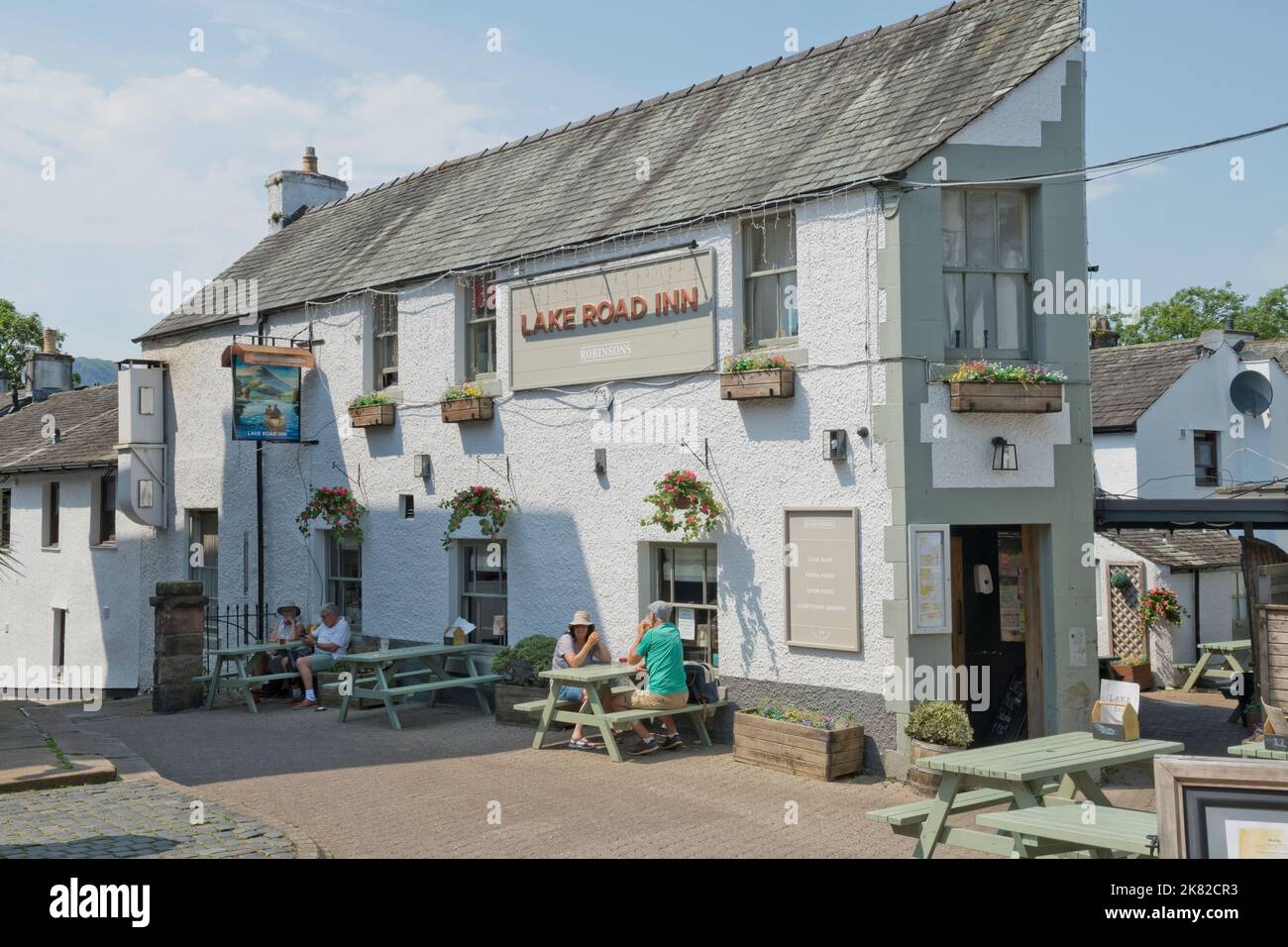 Touristen Wanderer Menschen trinken sitzen entspannen vor dem Lake Road Inn Pub in der Innenstadt Straße im Sommer Keswick England Großbritannien Stockfoto