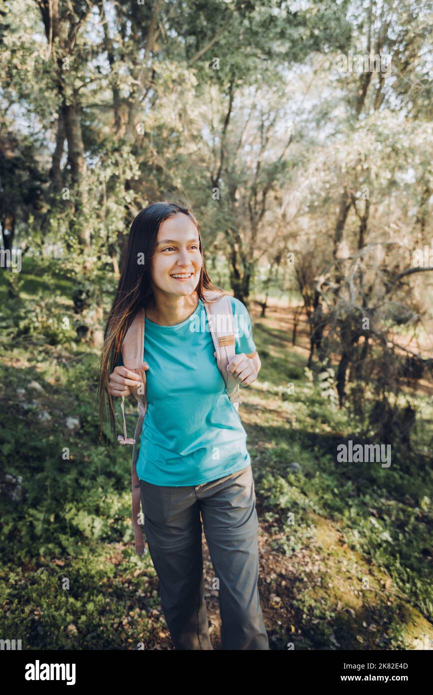 Selbstvertrauen. Teenager-Mädchen, die Kamera mit Rucksack mit heiterem Lächeln im Wald zu suchen. Stockfoto