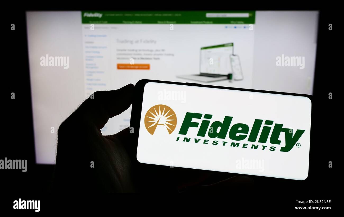 Person, die Mobiltelefon mit dem Logo des US-Unternehmens Fidelity Investments (FMR LLC) auf dem Bildschirm vor der Geschäftswebseite hält. Konzentrieren Sie sich auf die Telefonanzeige. Stockfoto