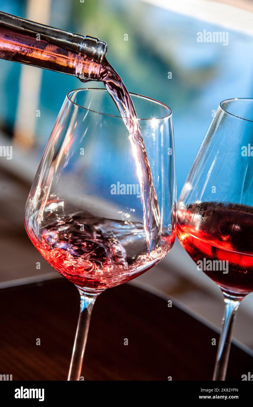 ROSÉWEIN Alfresco Gießen frische Gläser Roséwein in sonnigen funkelnden sonnen Alfresco Urlaub Sommer Schwimmbad Terrasse Lage. Stockfoto