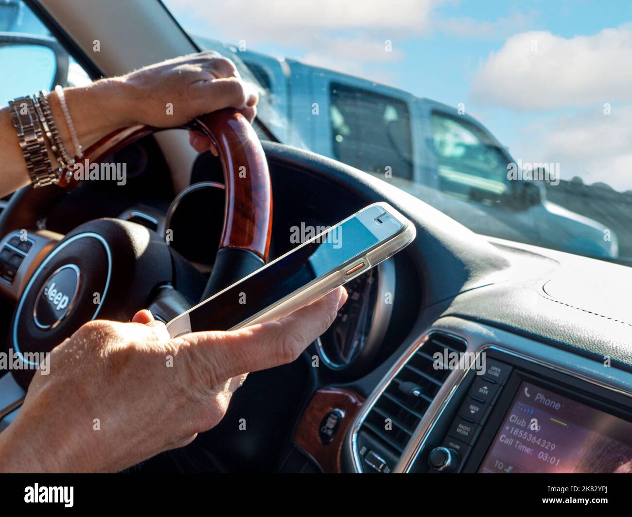AUTOFAHRER SMS-SMARTPHONE Weibliche Fahrer im Linksverkehr Fahrzeug SMS mit Smartphone während der Fahrt auf dem belebten kalifornischen Highway California USA Stockfoto