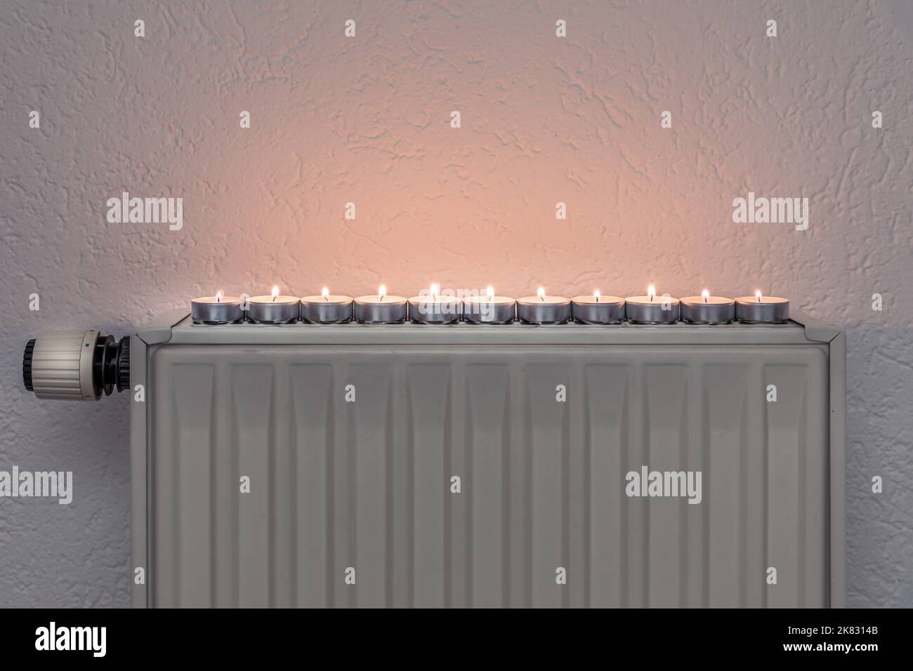 Teekerzen auf einem Wandheizgerät, Konzept alternativer Heeating-Möglichkeiten während der Energiekrise und Abschalten der regulären Heizquellen Stockfoto