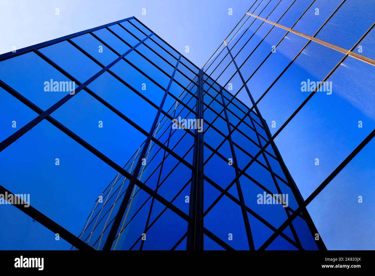 Geschäftsgebäude mit reflektierenden Glasfenstern, die den blauen Himmel reflektieren Stockfoto