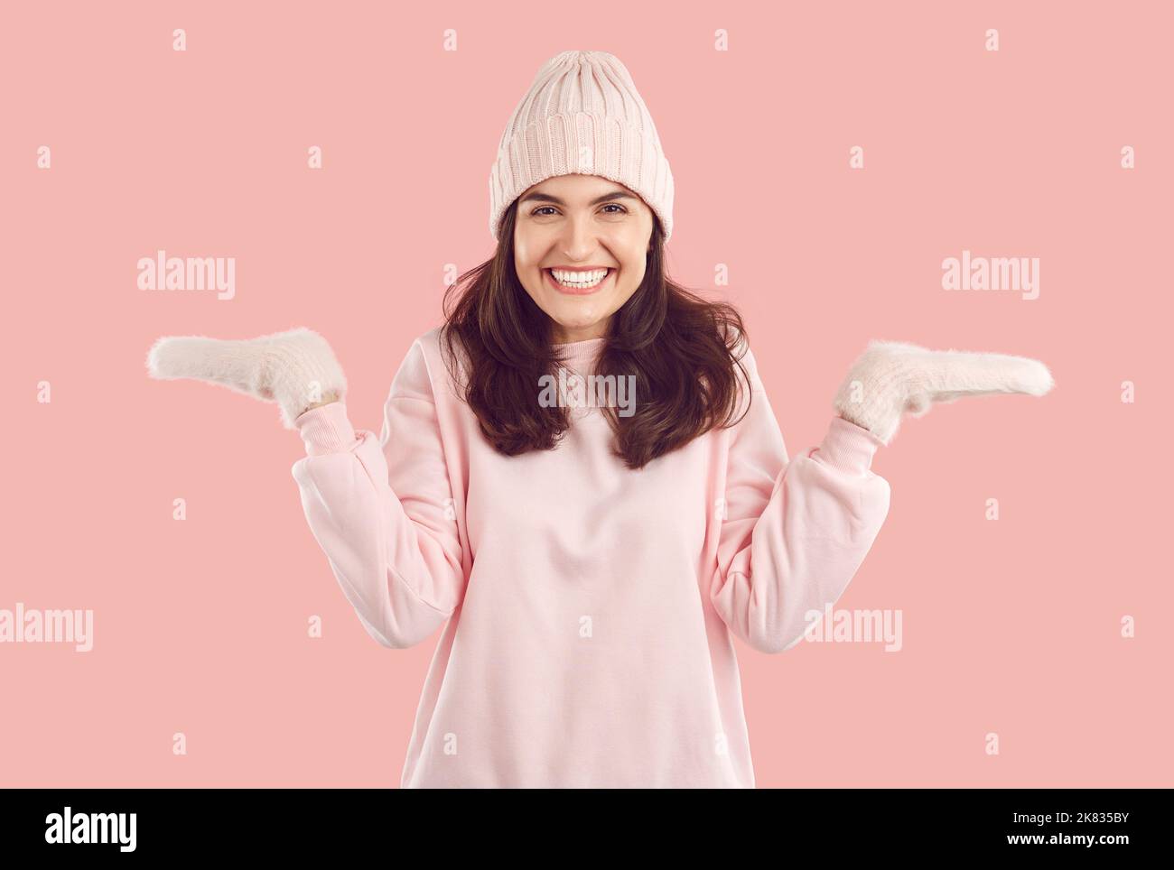 Glückliche Frau in rosa Winterhut und Fäustlinge bieten zwischen zwei Optionen wählen Stockfoto
