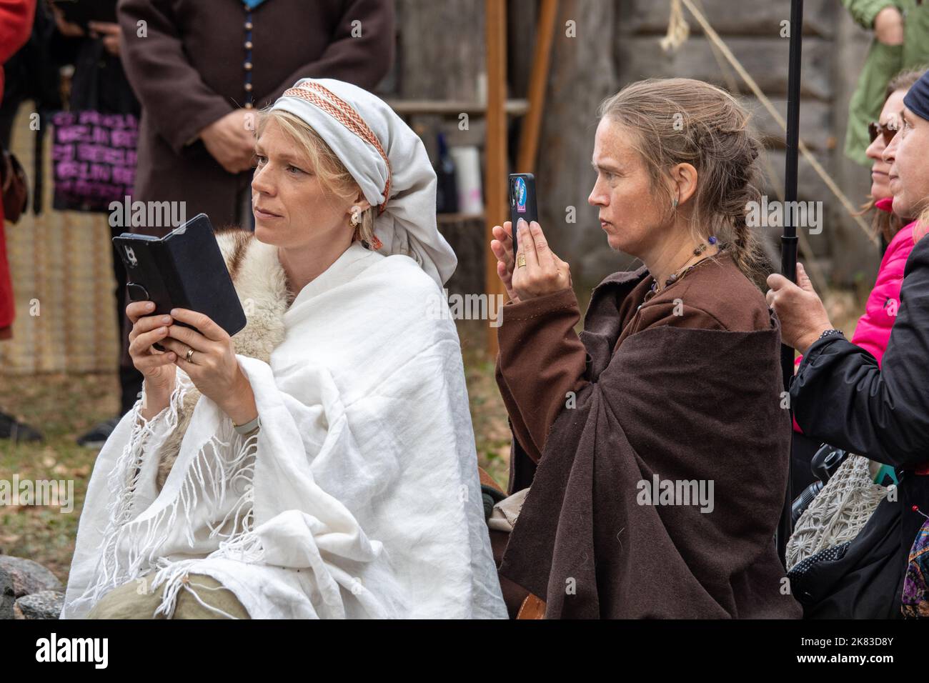 Frauen mit Mobiltelefonen auf dem Pukkisaari Iron Age Market Reenactment im Stadtteil Vähä-Meilahti in Helsinki, Finnland Stockfoto