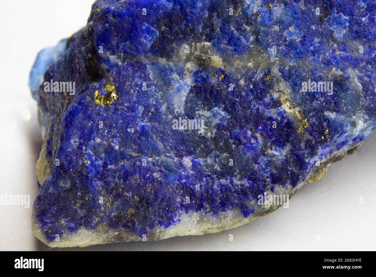 Roher Lapislazuli-Felsen auf weißem Hintergrund. Unpoliertes Stück Lapislazuli auf weißem Hintergrund. Lapislazuli mit Pyritflecken. Stockfoto