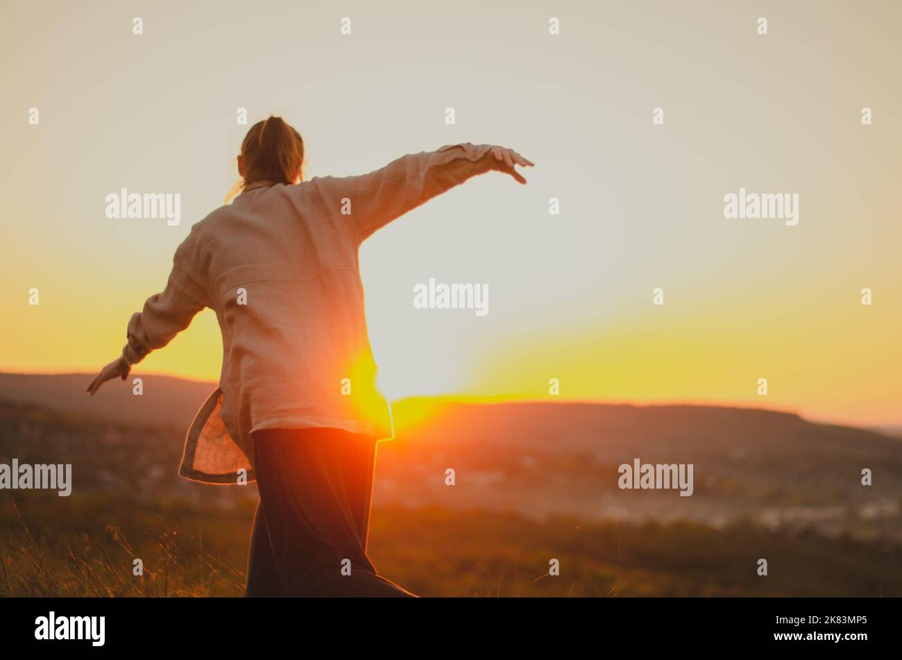 Frau macht intuitive Bewegung auf Hügel bei Sonnenuntergang Stockfoto