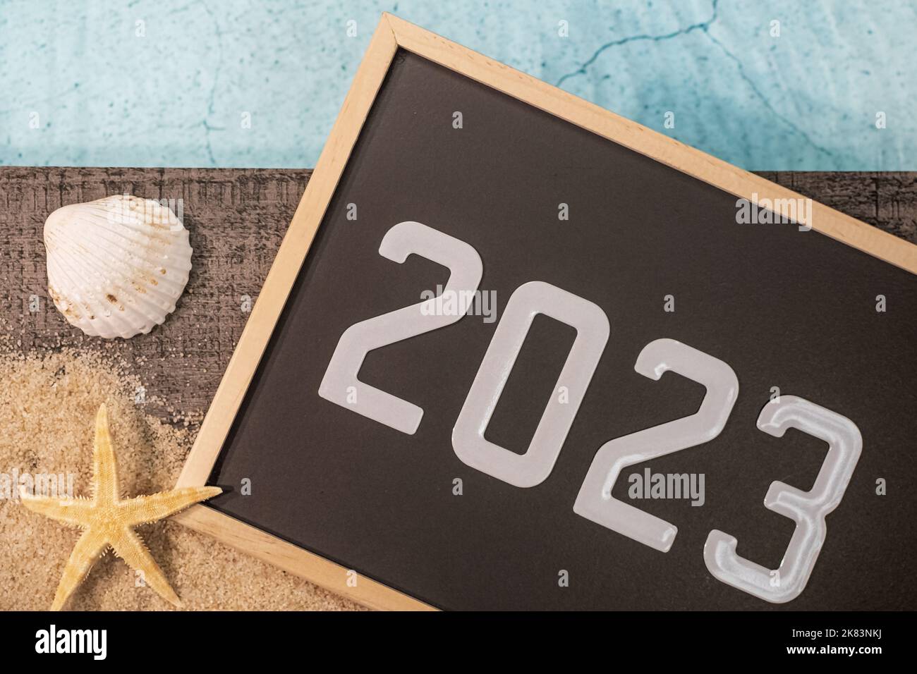 Frohes neues Jahr 2023 Konzept mit einer Schale und einem Seestern am Pool. Winterurlaub in der Sonne. Stockfoto
