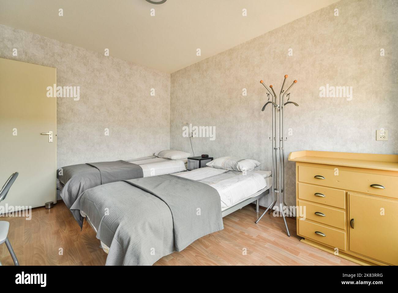 Modernes Bett mit bequemer Matratze und weichen Kissen neben Nachttisch und elektrischem Kamin im geräumigen Schlafzimmer Stockfoto