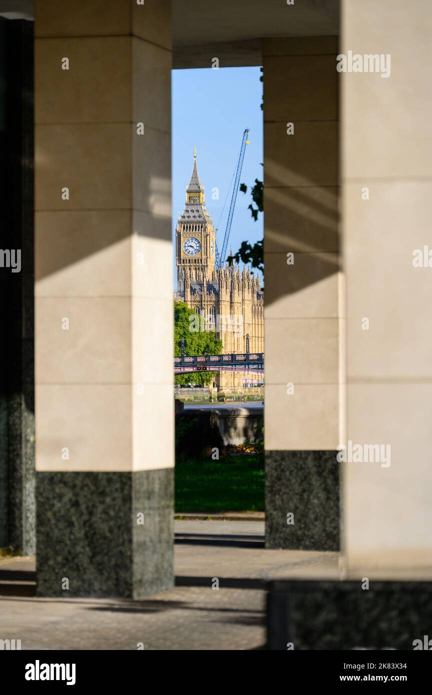 London - 18. September 2022: Die Houses of Parliament und ein Baukran zwischen den Säulen eines Bürogebäudes Stockfoto