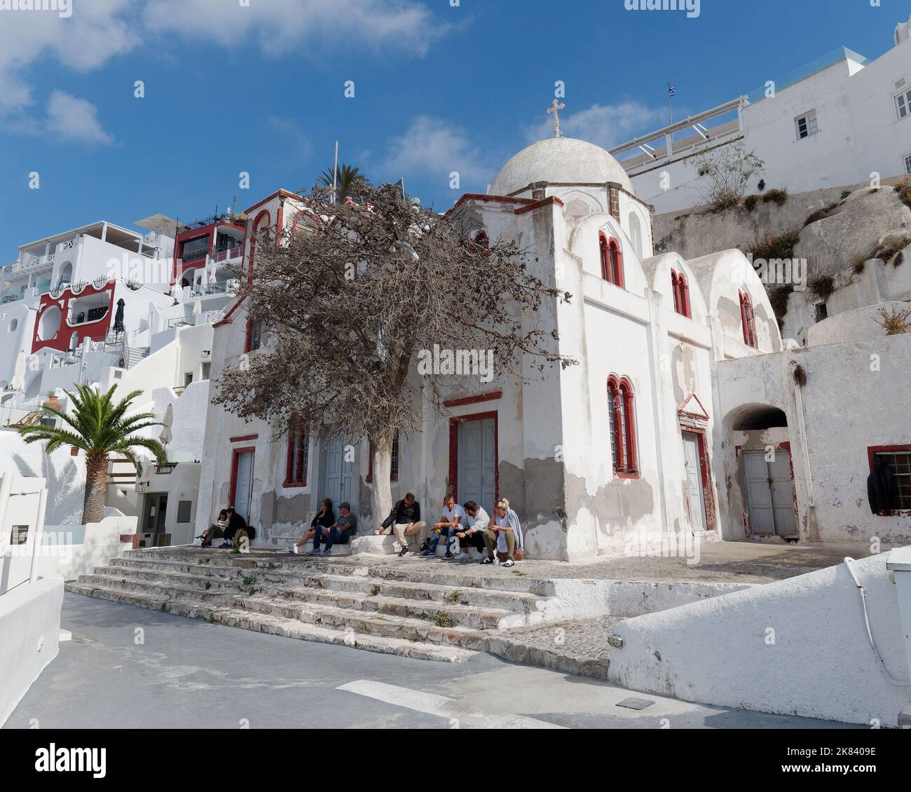Die Menschen sitzen neben einer Kirche in der Stadt Fira, der griechischen Kykladen-Insel Santorin in der Ägäis Stockfoto