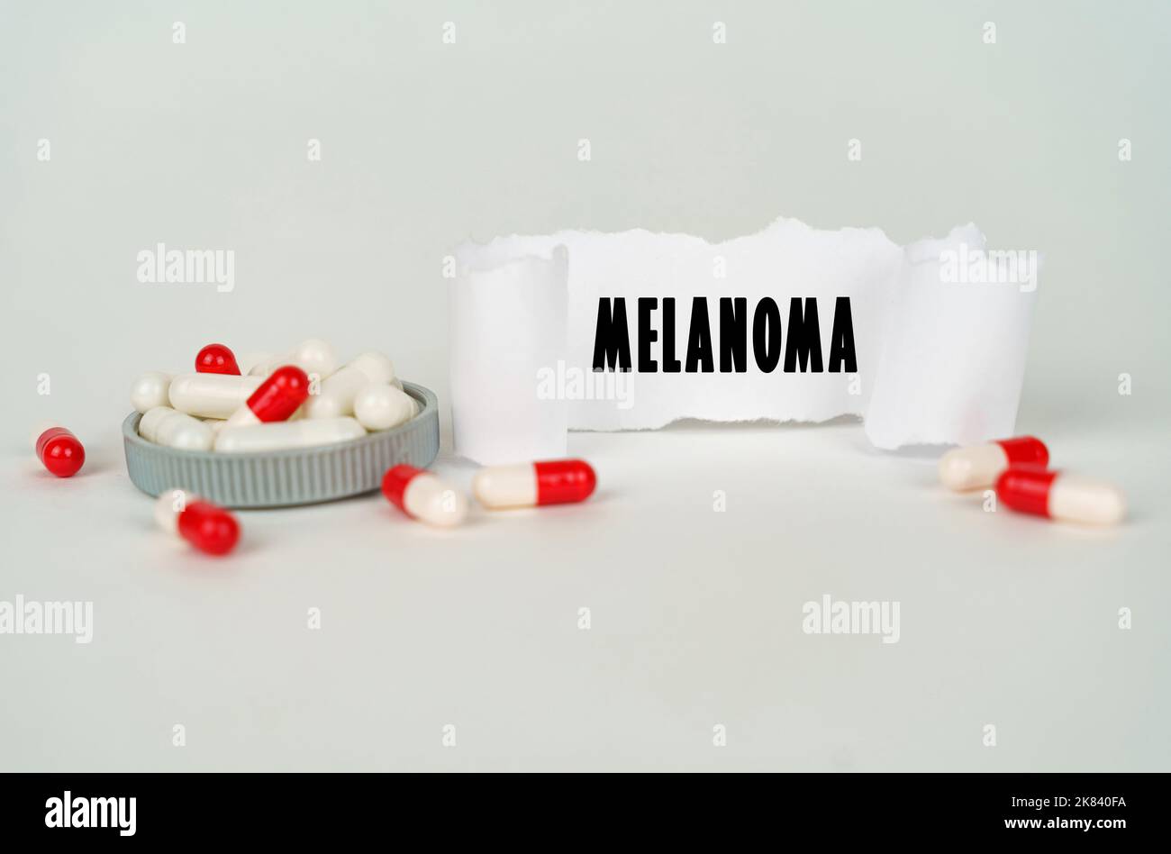 Medizinisches Konzept. Auf grauem Hintergrund medizinische Kapseln und ein Pappteller mit der Aufschrift - melanoma Stockfoto