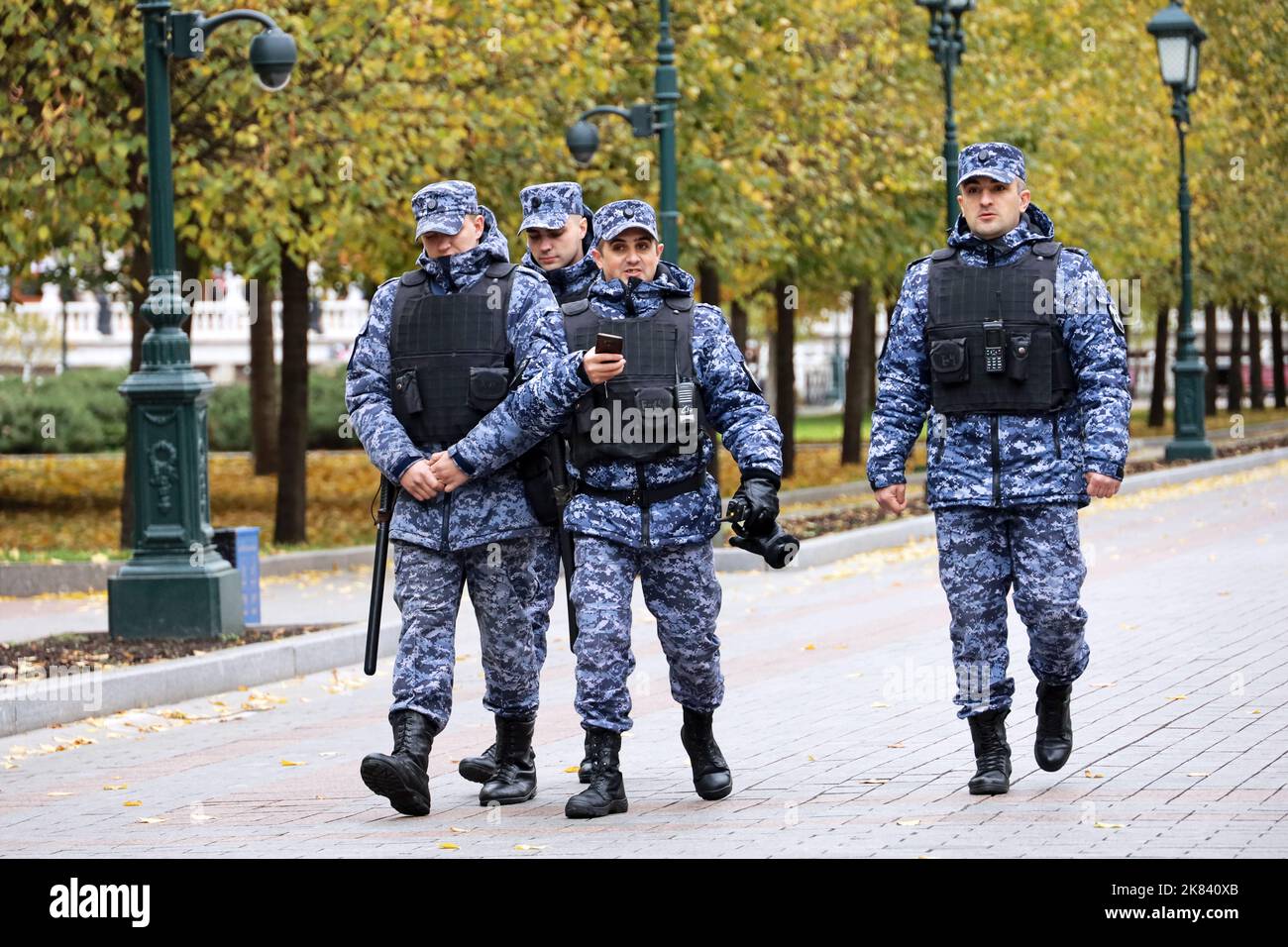 Soldaten russischer Streitkräfte in Tarnkleidung und kugelsicheren Westen, die im Herbst die Straße der Stadt entlang gehen Stockfoto