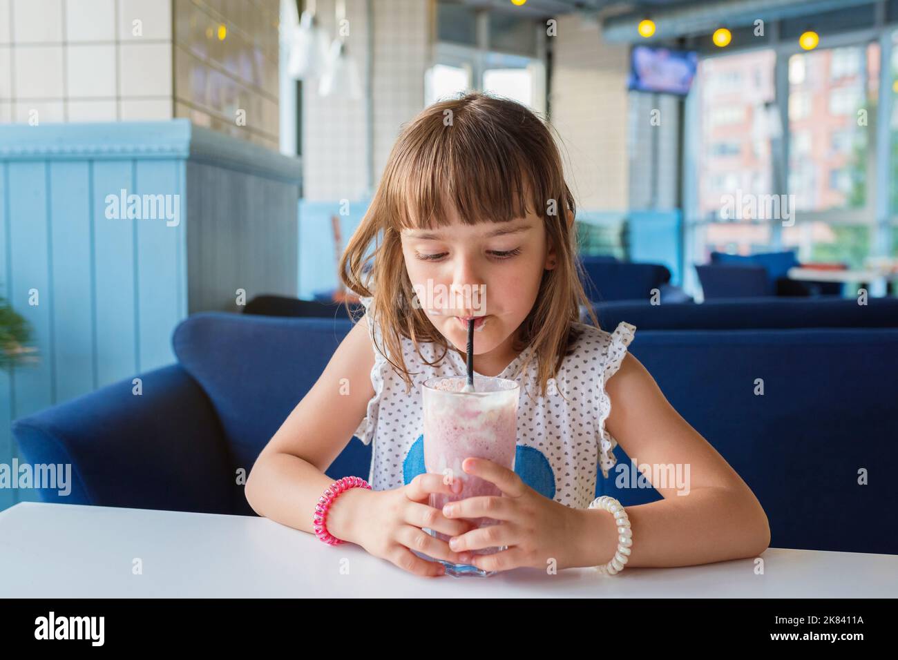 Ein Mädchen in einem Café, das einen Milchshake trinkt. Gesunde Ernährung Stockfoto
