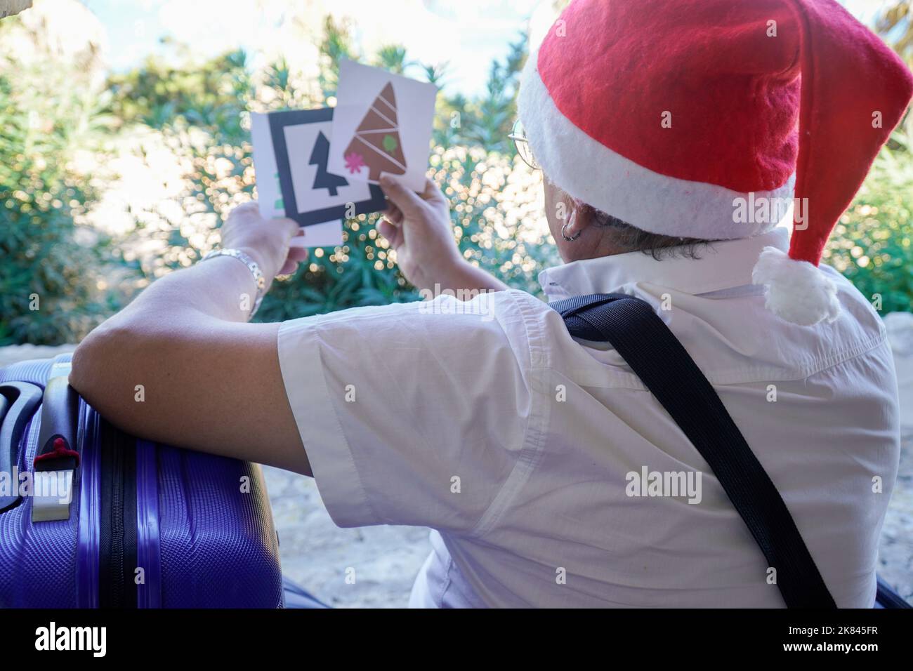 Glücklicher Senior mit weihnachtsmütze und Koffer in den weihnachtsferien Stockfoto