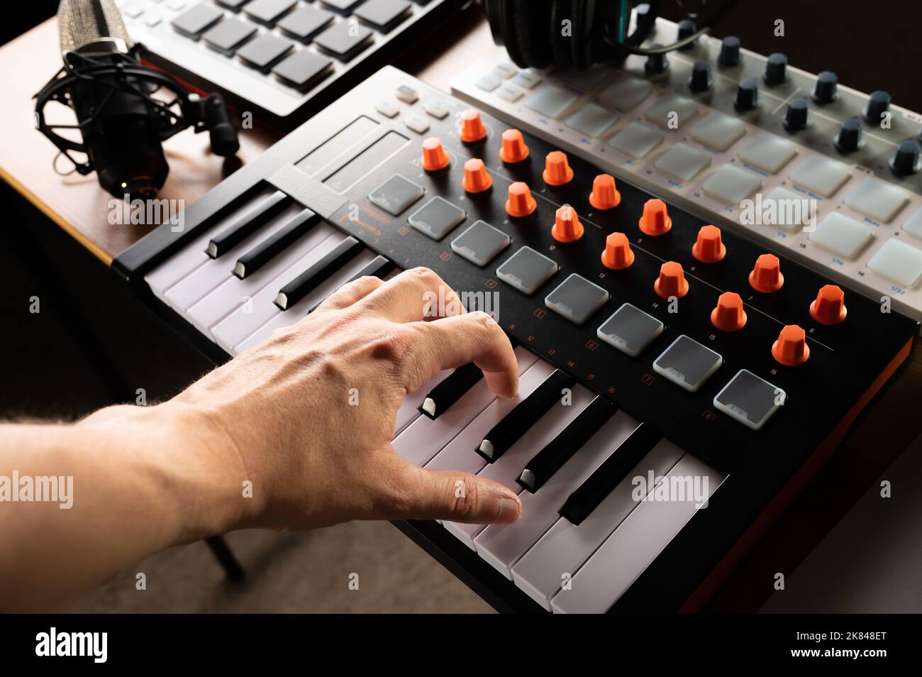Studioausstattung für Aufnahmestudio, Musikstudio. Die Hand des Musikers auf dem Midi-Keyboard. Studio-Kopfhörer. Aufnahme eines Musikalbums, Podcasts. Werbung Stockfoto