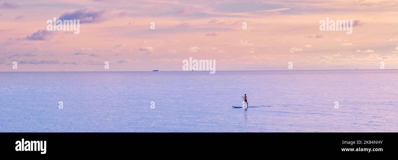 Männer paddeln während des Sonnenuntergangs auf einem Brett auf Koh Kood, einer tropischen Insel in der Provinz trat Ost-Thailand Stockfoto