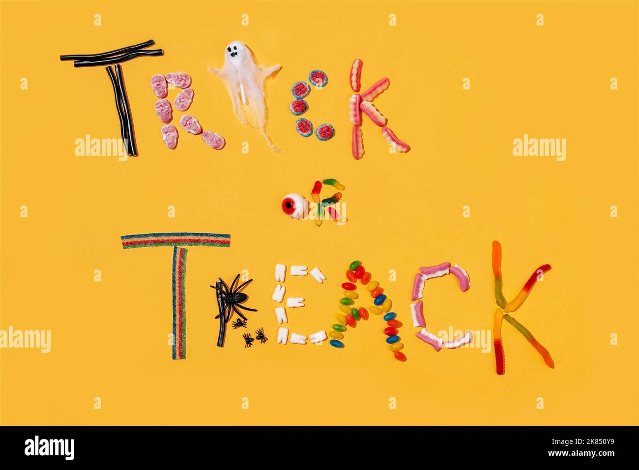 Trick or Treat. Süße Süßigkeiten auf gelbem Hintergrund. Halloween-Party Stockfoto