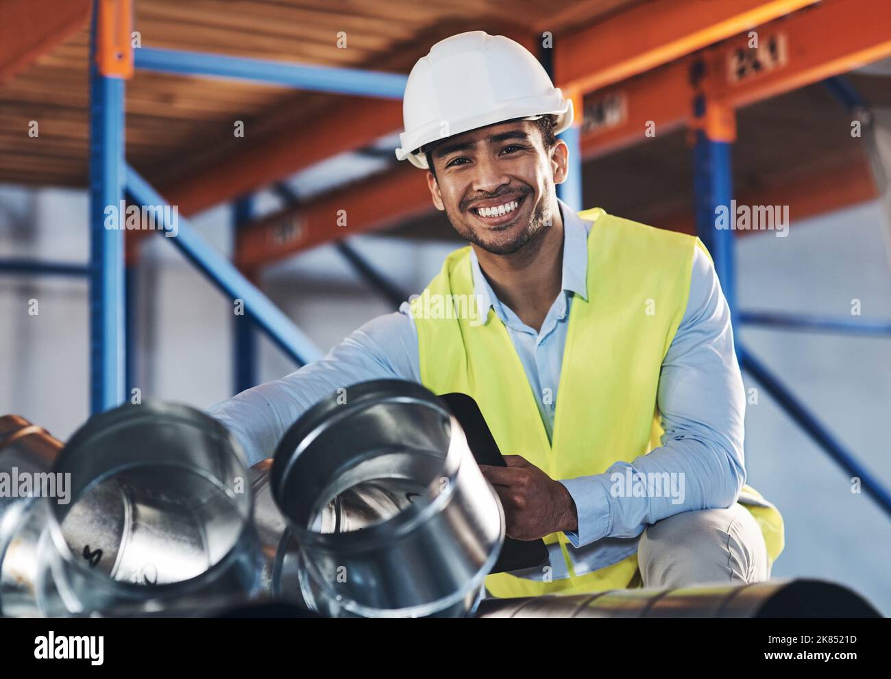 Ein hübscher, junger Auftragnehmer, der sich hinhockend im Lager anlegt und eine Bestandsaufnahme macht. Stockfoto