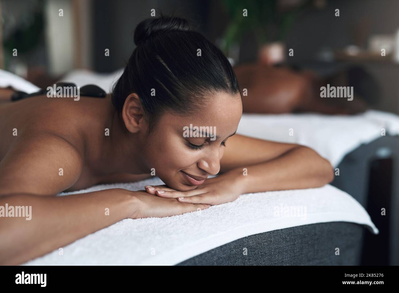 Alles ist ruhig und ich liebe es. Eine junge Frau bekommt eine Hot Stone Massage in einem Spa. Stockfoto