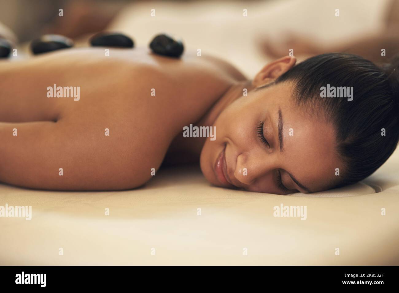 Entspannen Sie Körper und Geist bei einem Wellnesstag. Eine junge Frau genießt eine Hot Stone Massage in einem Spa. Stockfoto