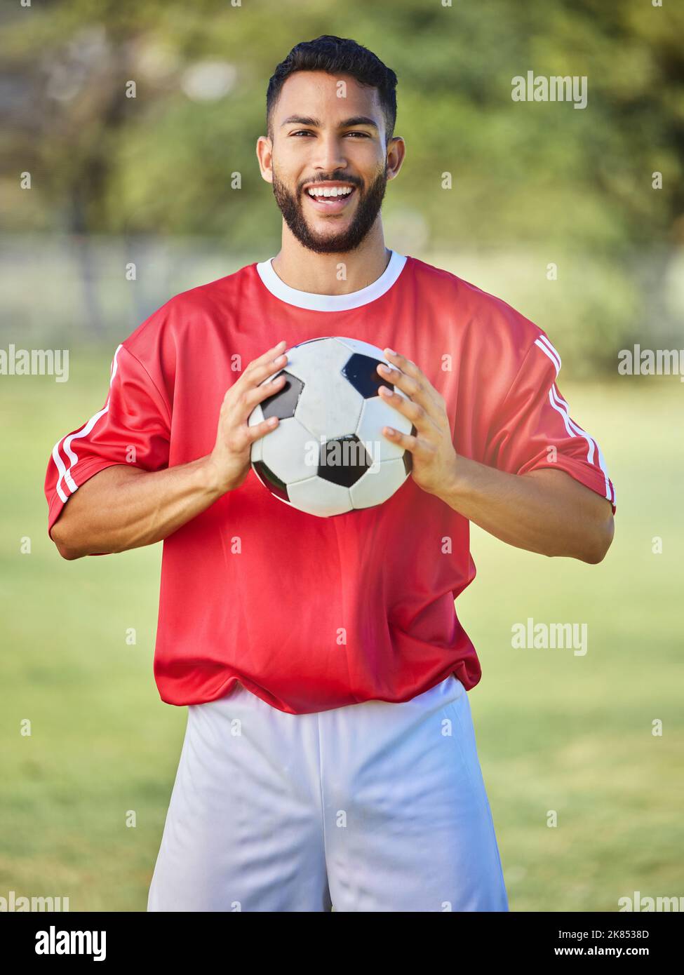 Fußball, Sport und Mann auf einem Feld für ein Spiel, Training oder Wettbewerb. Porträt eines jungen, glücklichen und begeisterten Athleten mit einem Fußball während einer Stockfoto