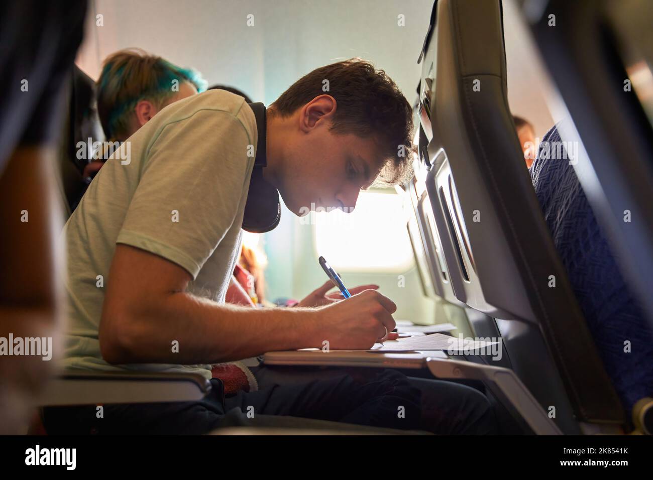 Tourist Hand Ausfüllen Einwanderungsformular auf dem Flug zu besuchen Zielland sitzen im Flugzeug. Mann schreibt Einreisegenehmigung oder Visum auf ein Papier auf einem Stockfoto