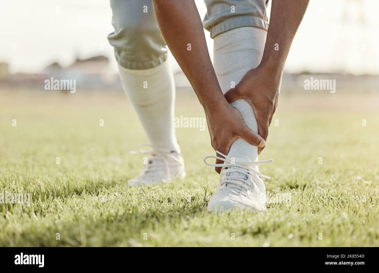 Sport, Feld und Mann mit Knöchelverletzung nach Spiel, Wettkampf oder Baseballtraining. Notfall, Trainingsunfall oder Sportler Beine in Schmerzen Stockfoto